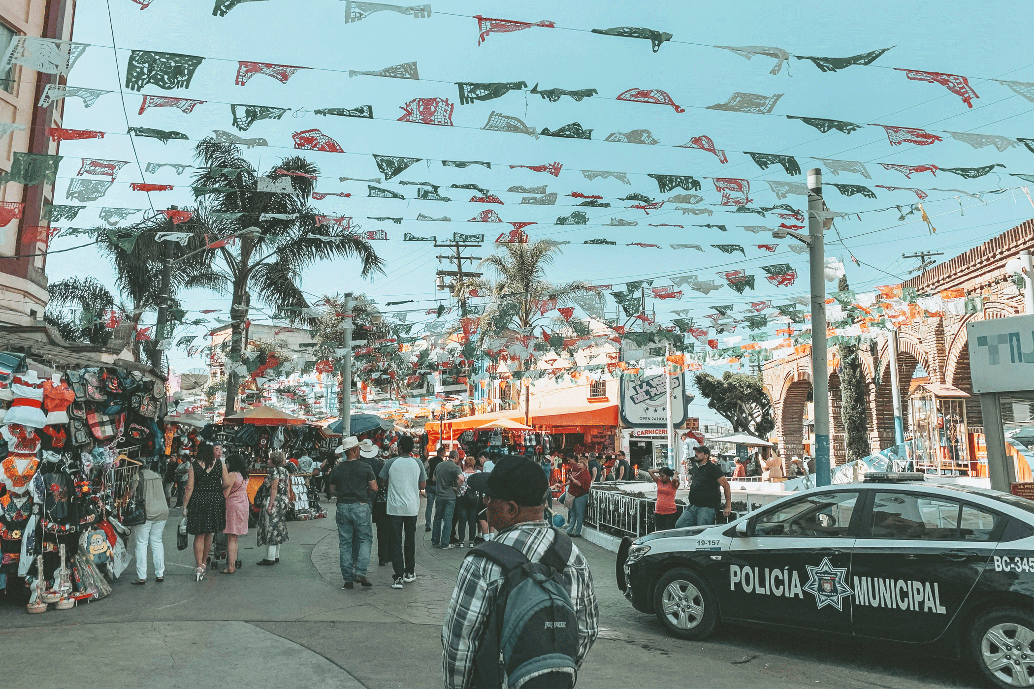 Drukke straat met veel mensen en een politieauto in Baja California in Mexico