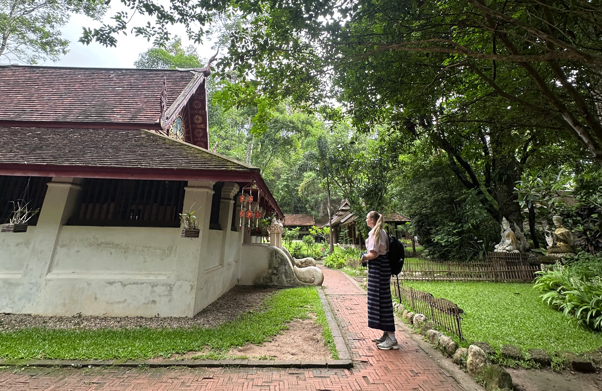 Hanna in traditionele kleding bezoekt een serene, groene tempel in Chiang Mai, Thailand.