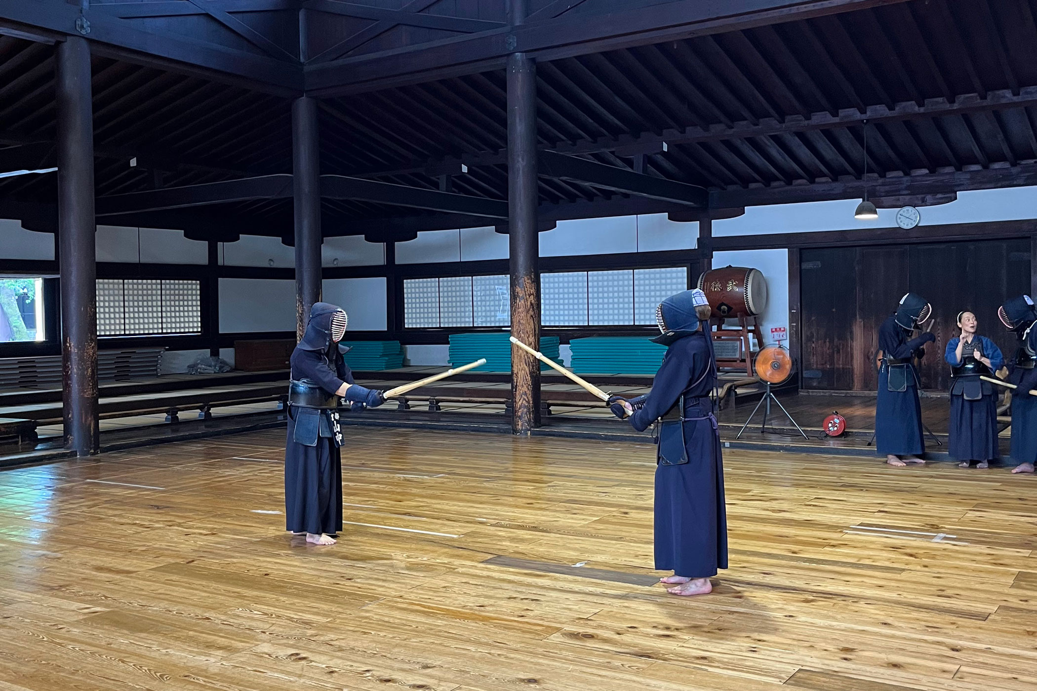 Twee mensen in samoeraikleding staan in een typische Japanse tempel met zwaarden in hun handen op een houten vloer.