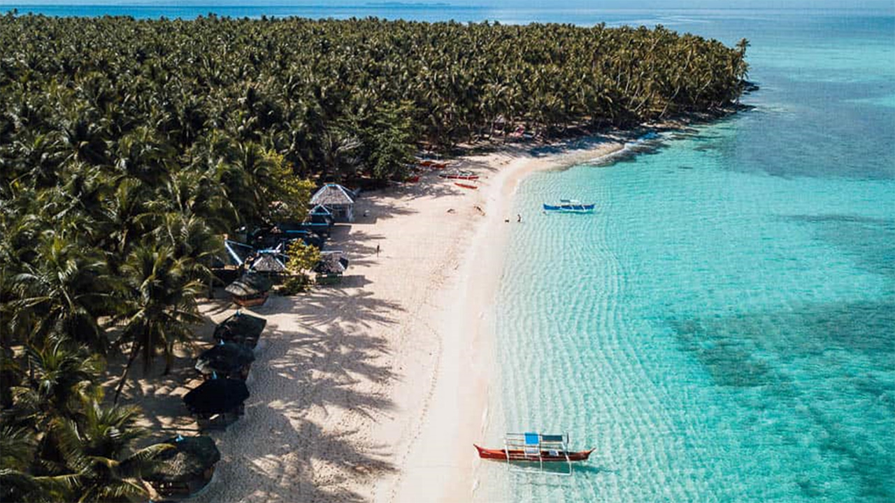 Pristine sandy beach with traditional boats in Siargao in the Philippines